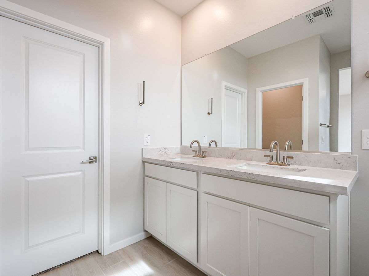 A bathroom with white cabinets.