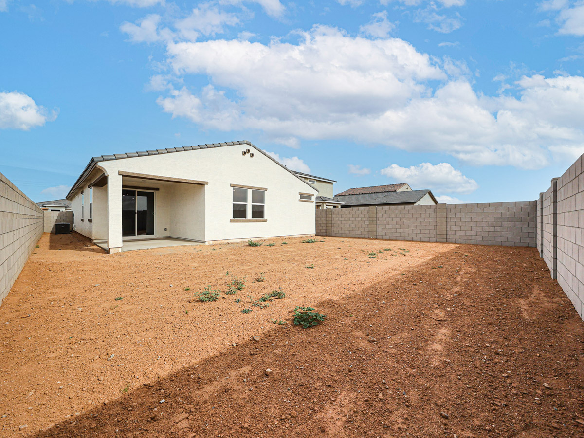 A dirt yard with a house in the background.