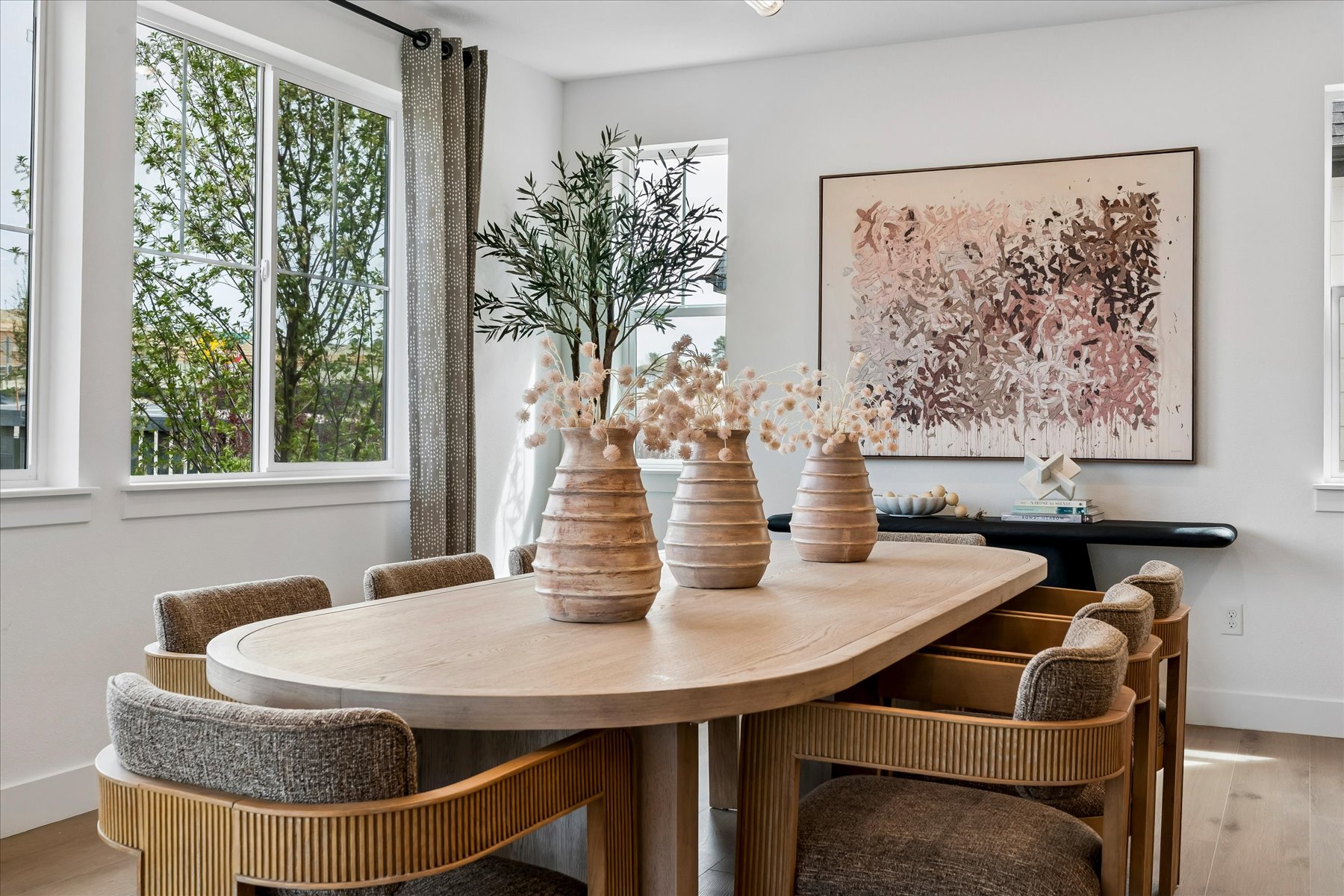 A dining room table with chairs and a vase of flowers.