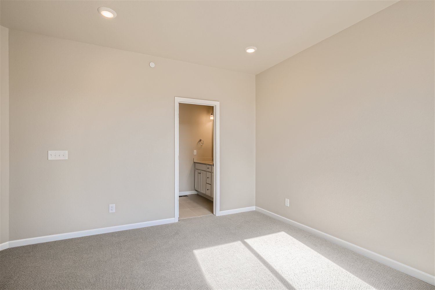 A room with a white tile floor and a white wall with a door.