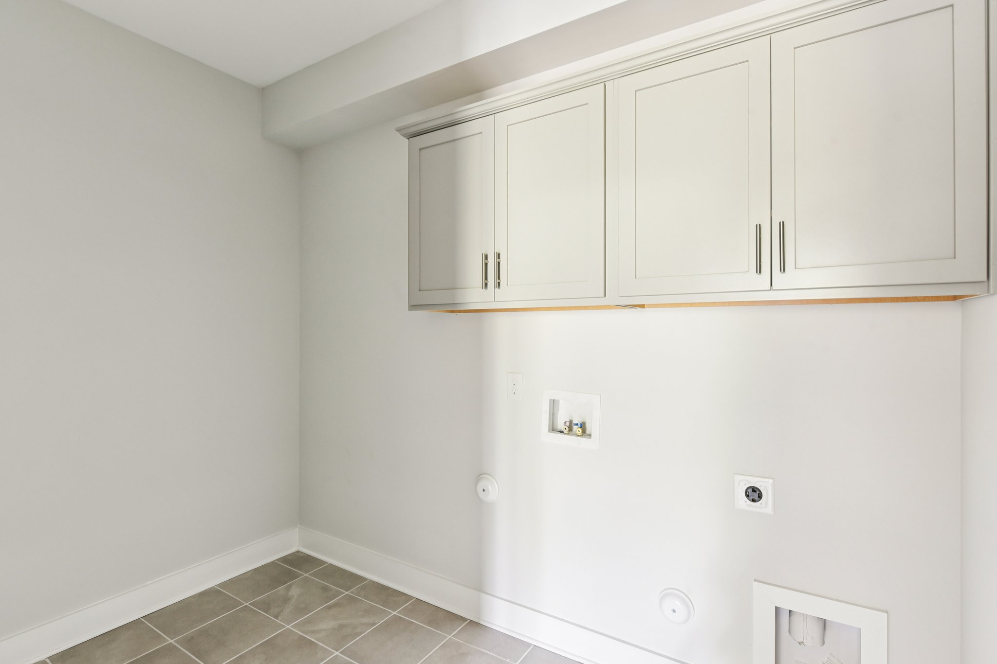 A white wall with white cabinets.
