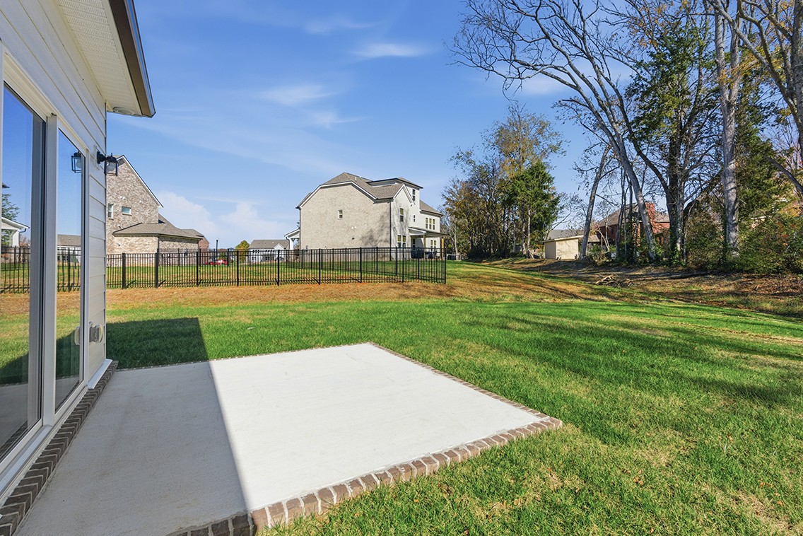 A fenced in yard with a house and trees.