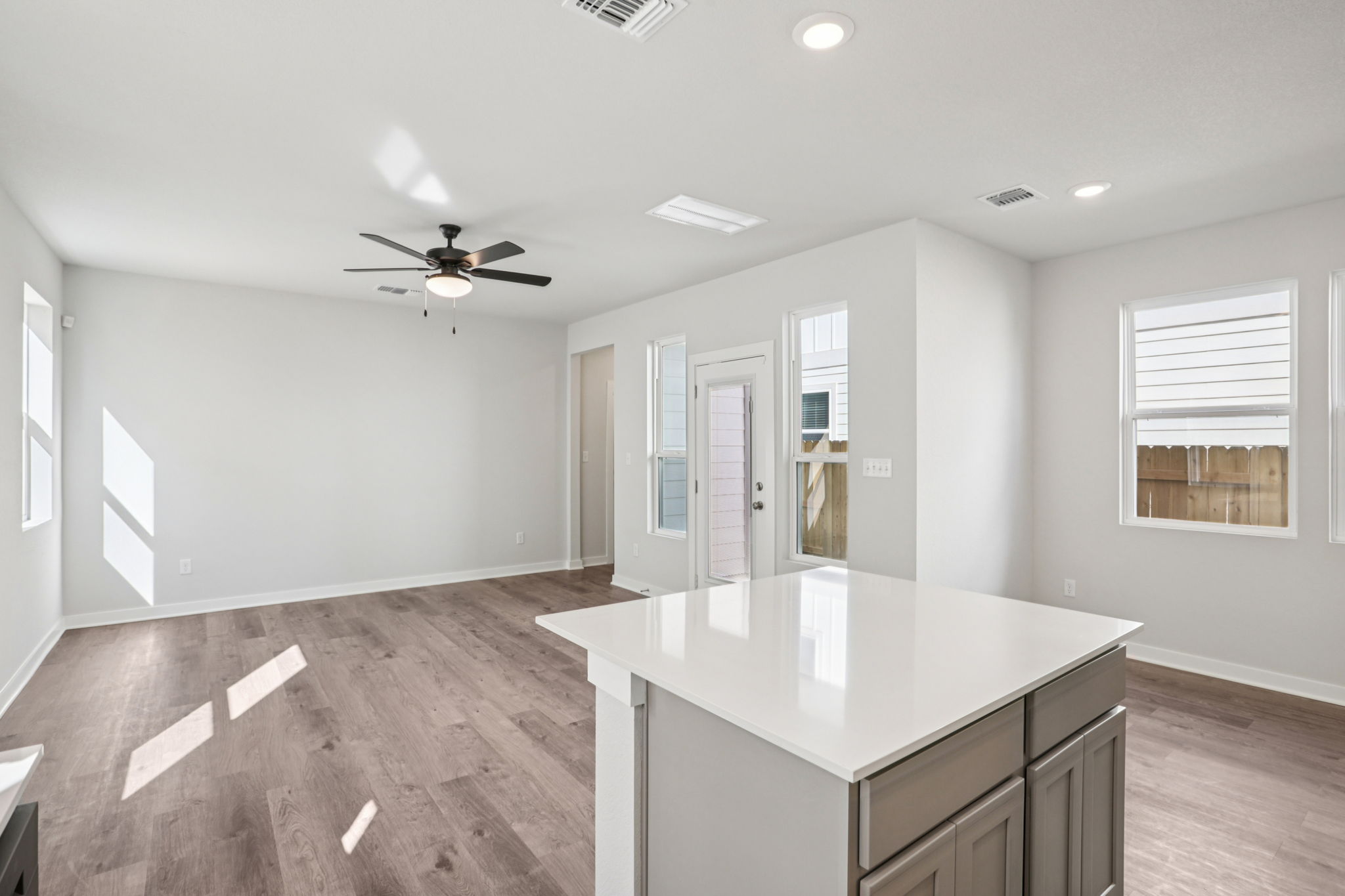 A large empty room with a large white counter and a ceiling fan.