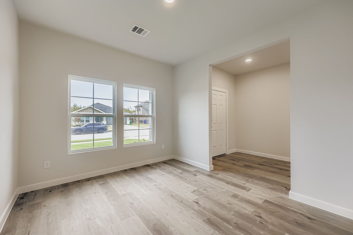 A room with a wood floor and a window with a view of the ocean.