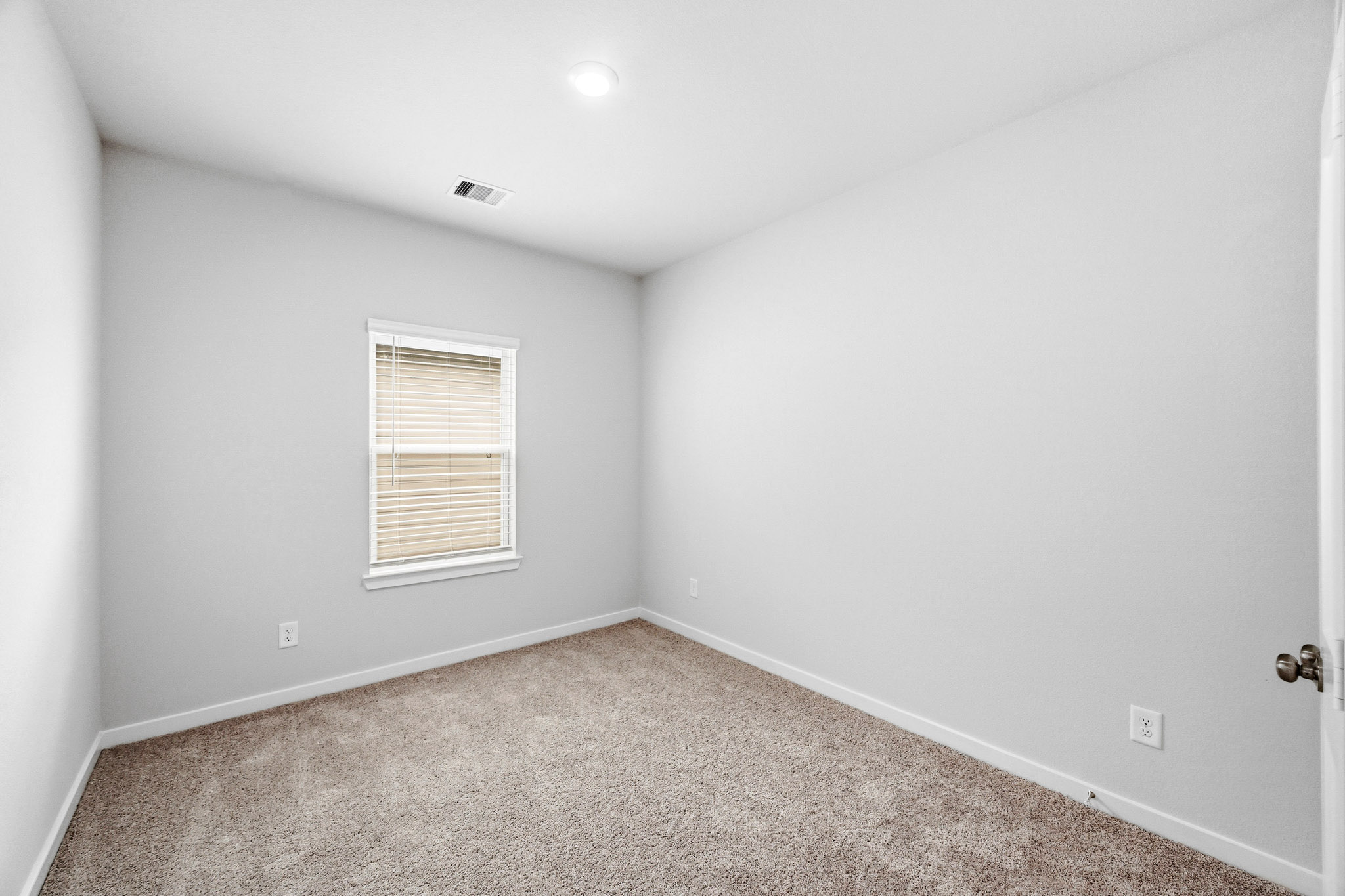 A room with a carpet and a window.