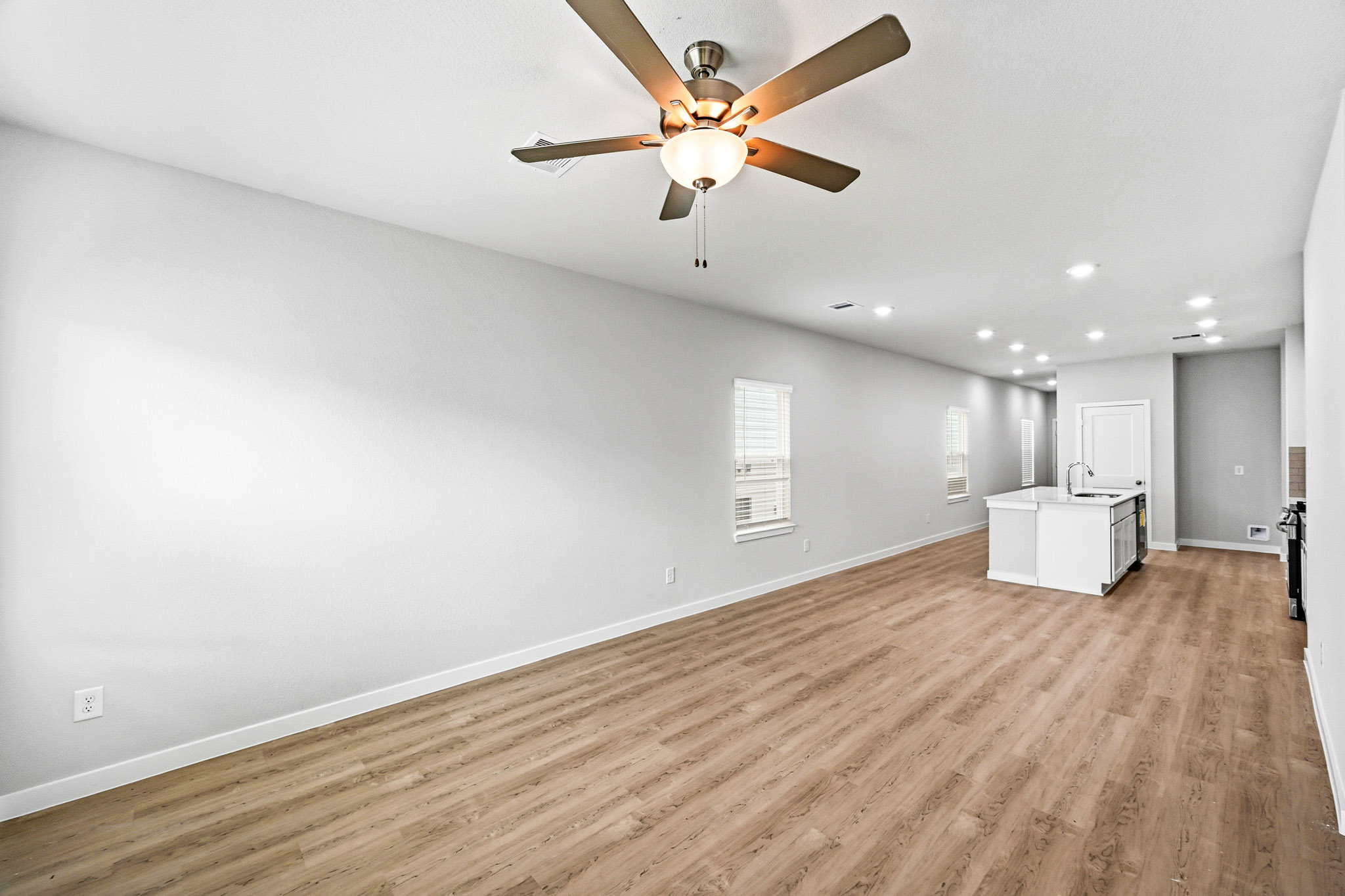 A room with a ceiling fan and a wood floor.