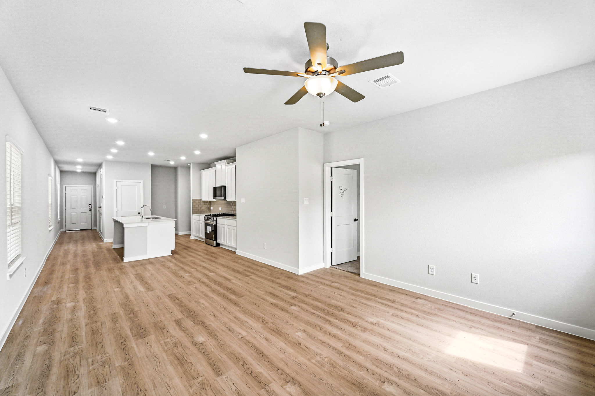 A large empty room with a ceiling fan and a wood floor.