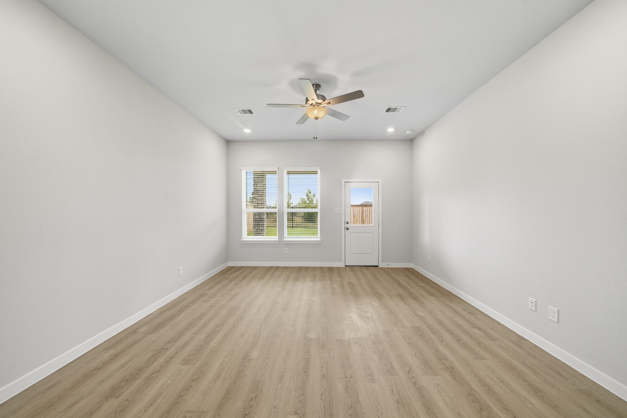 A room with a ceiling fan and a wood floor.