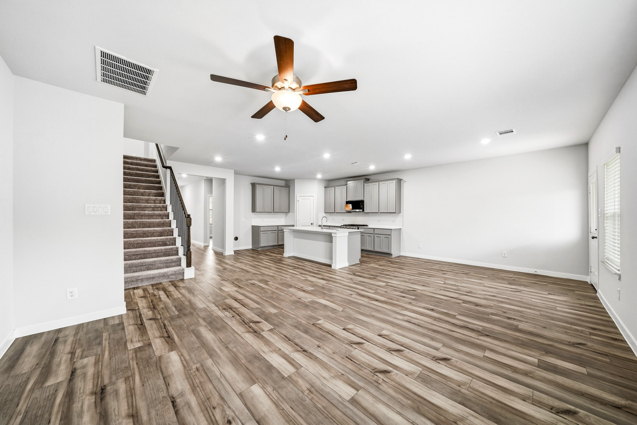 A large empty room with a wood floor and a ceiling fan.