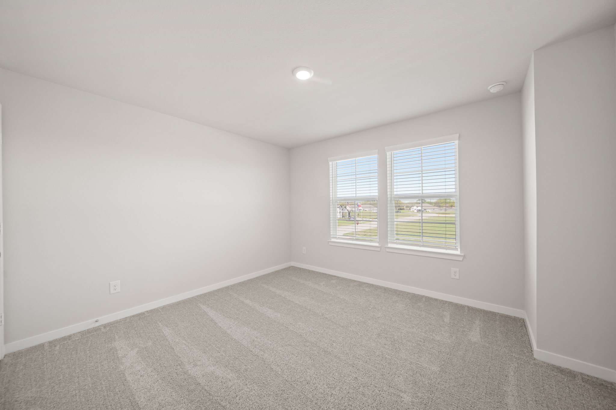 A room with a window and a white wall.