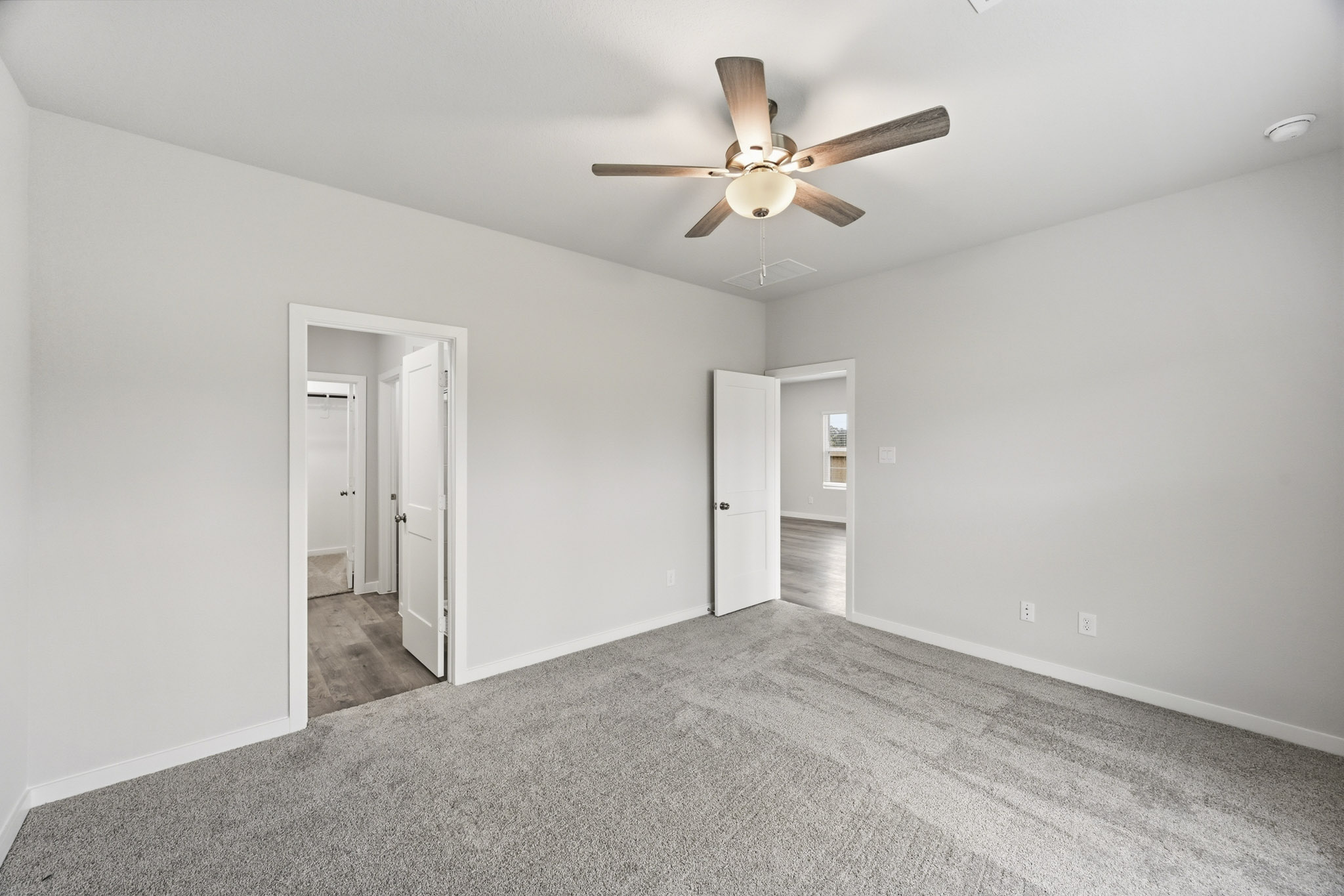 A room with a ceiling fan and a door.