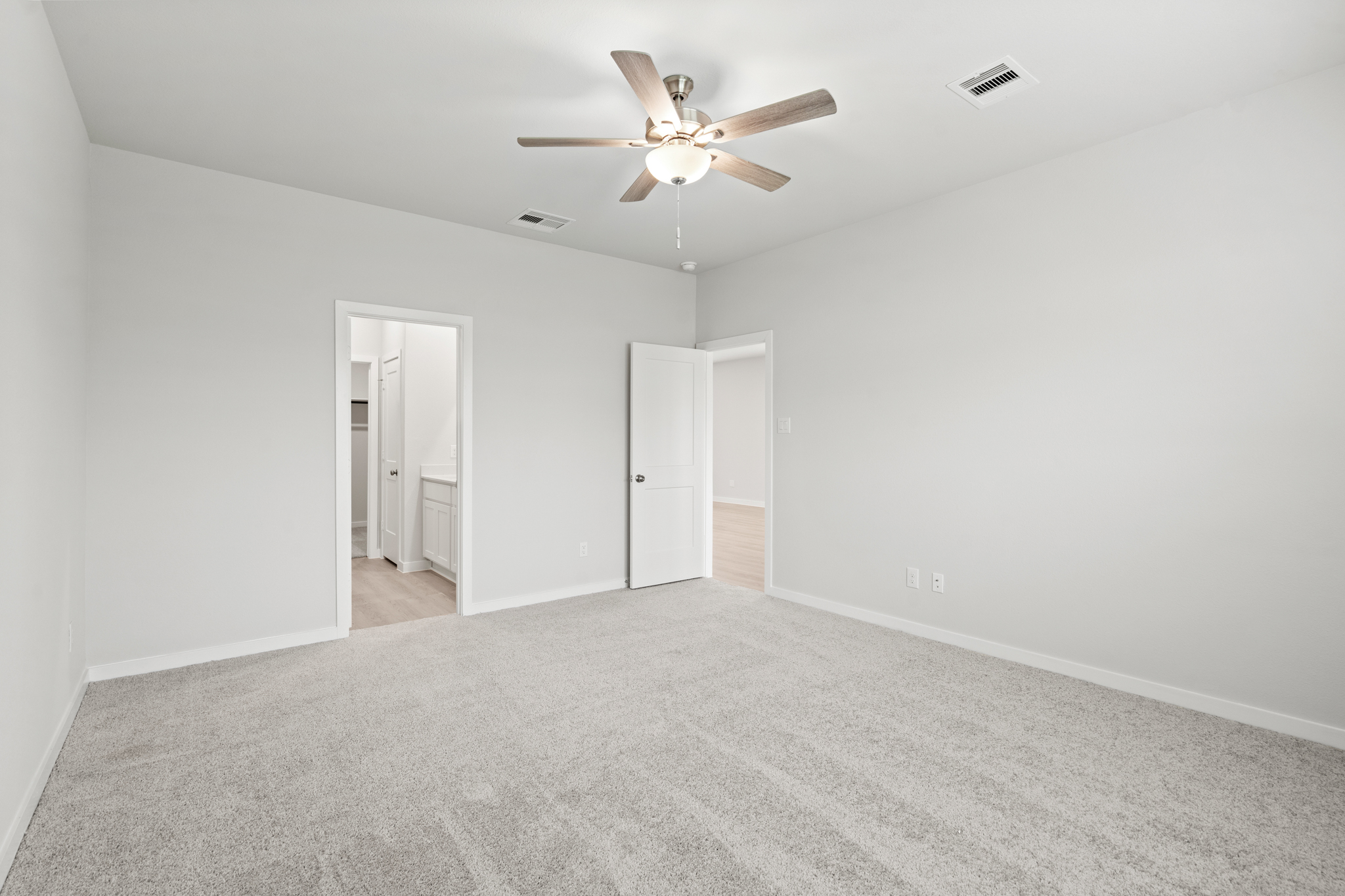 A room with a ceiling fan and a carpet.