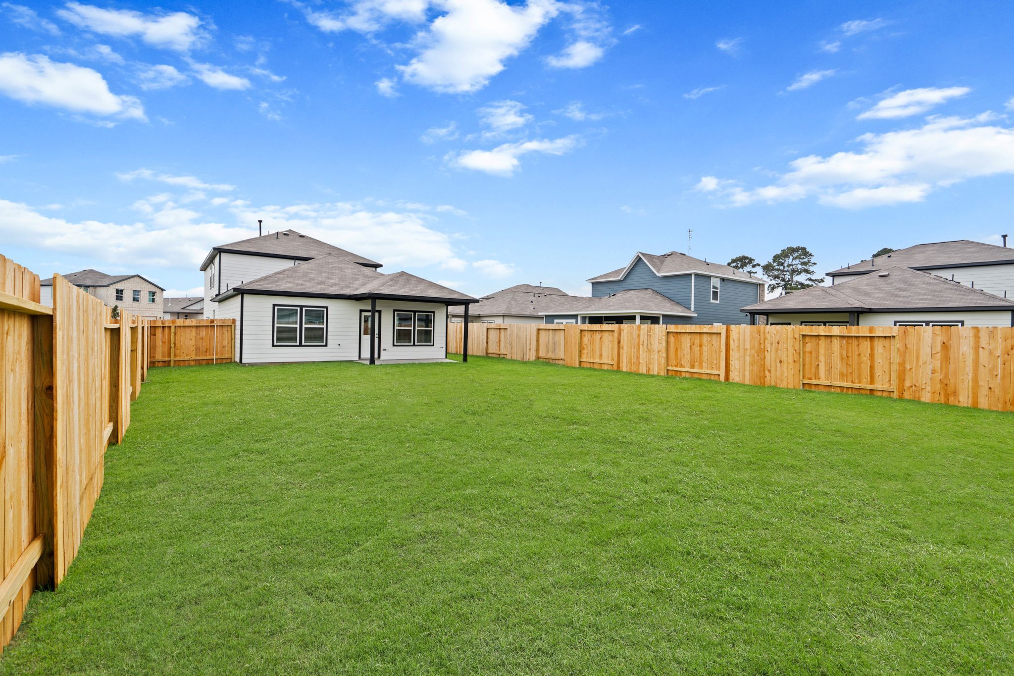 A grassy yard with houses in the background.