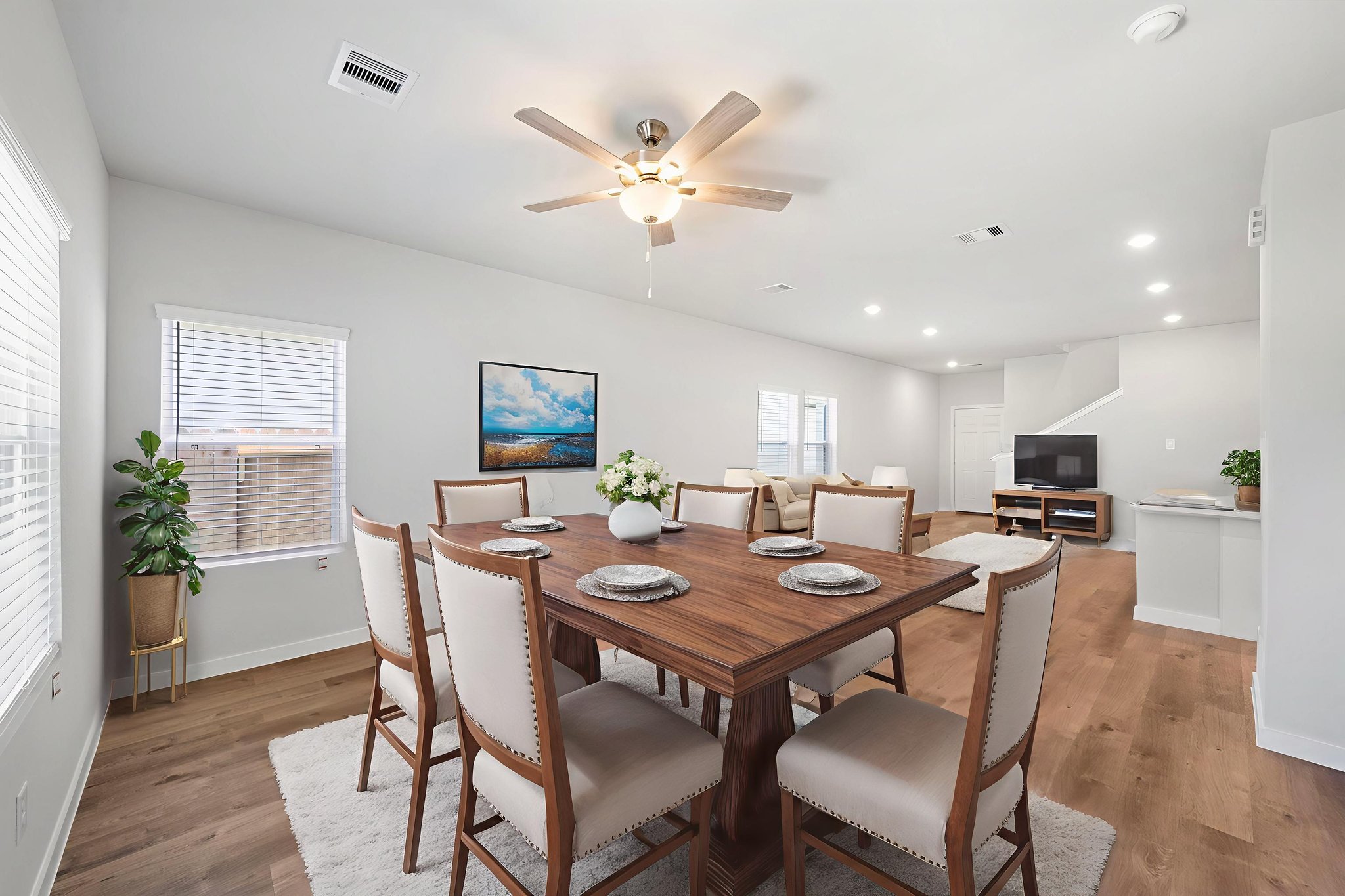 A dining room table with plates and a fan in the background.