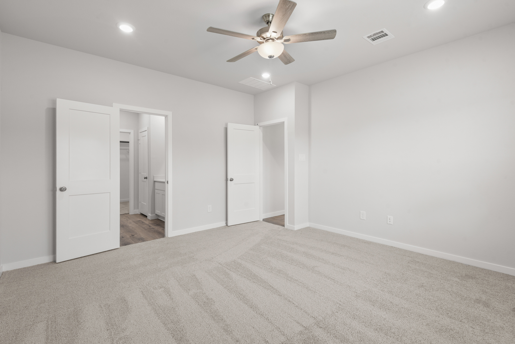 A room with a ceiling fan and white cabinets.