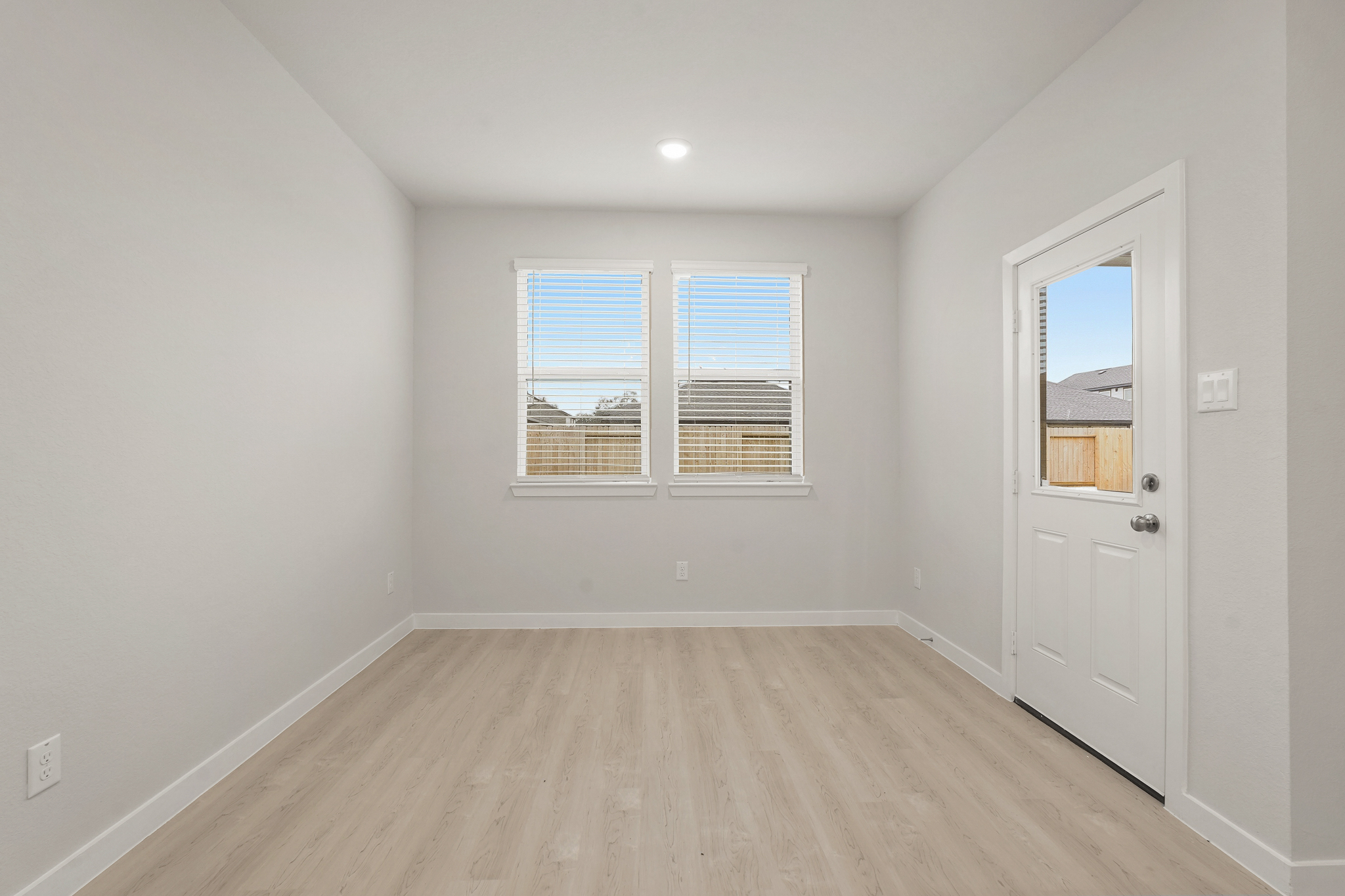 A room with a wood floor and a white door with a window.