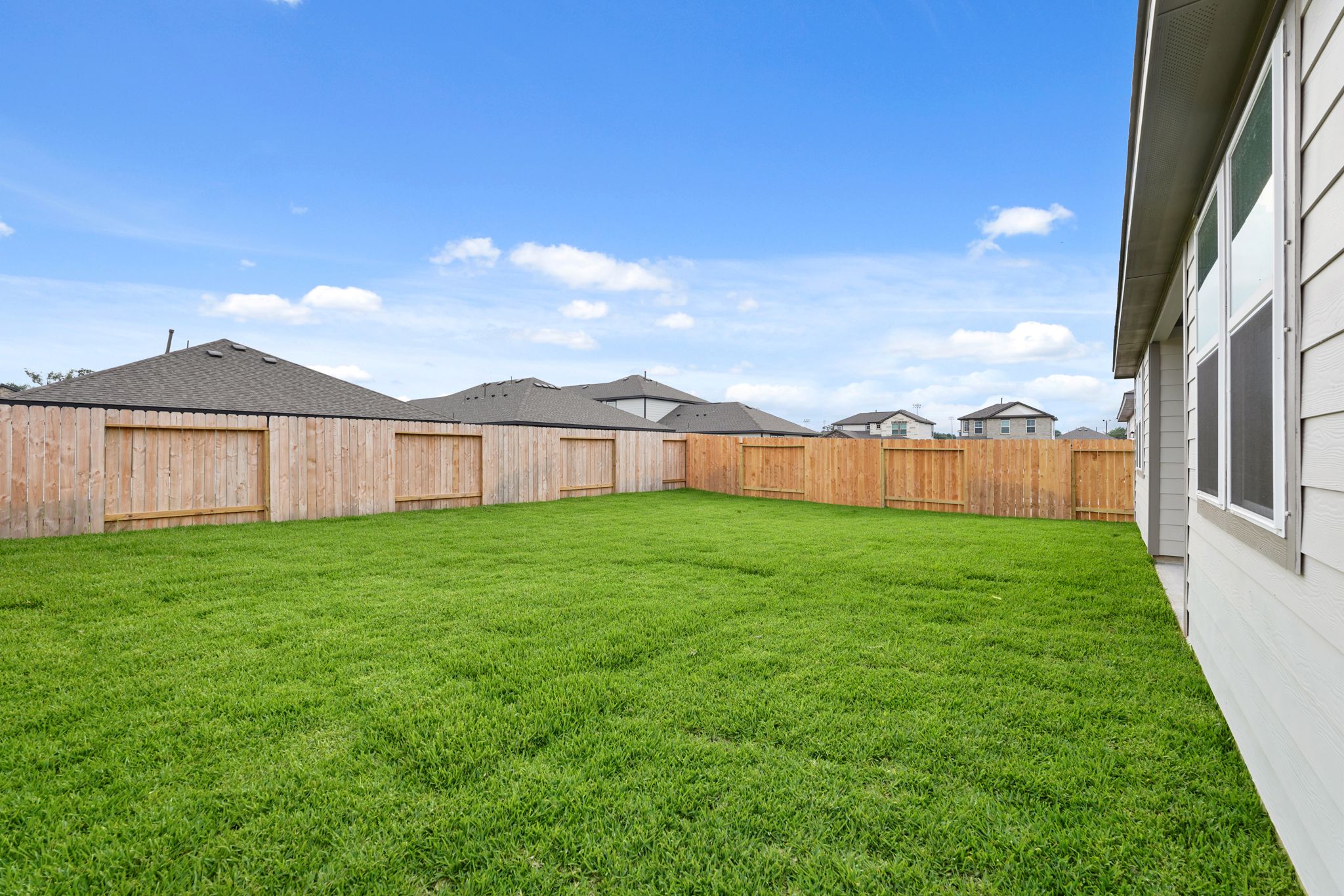 A fenced in yard with a house in the background.