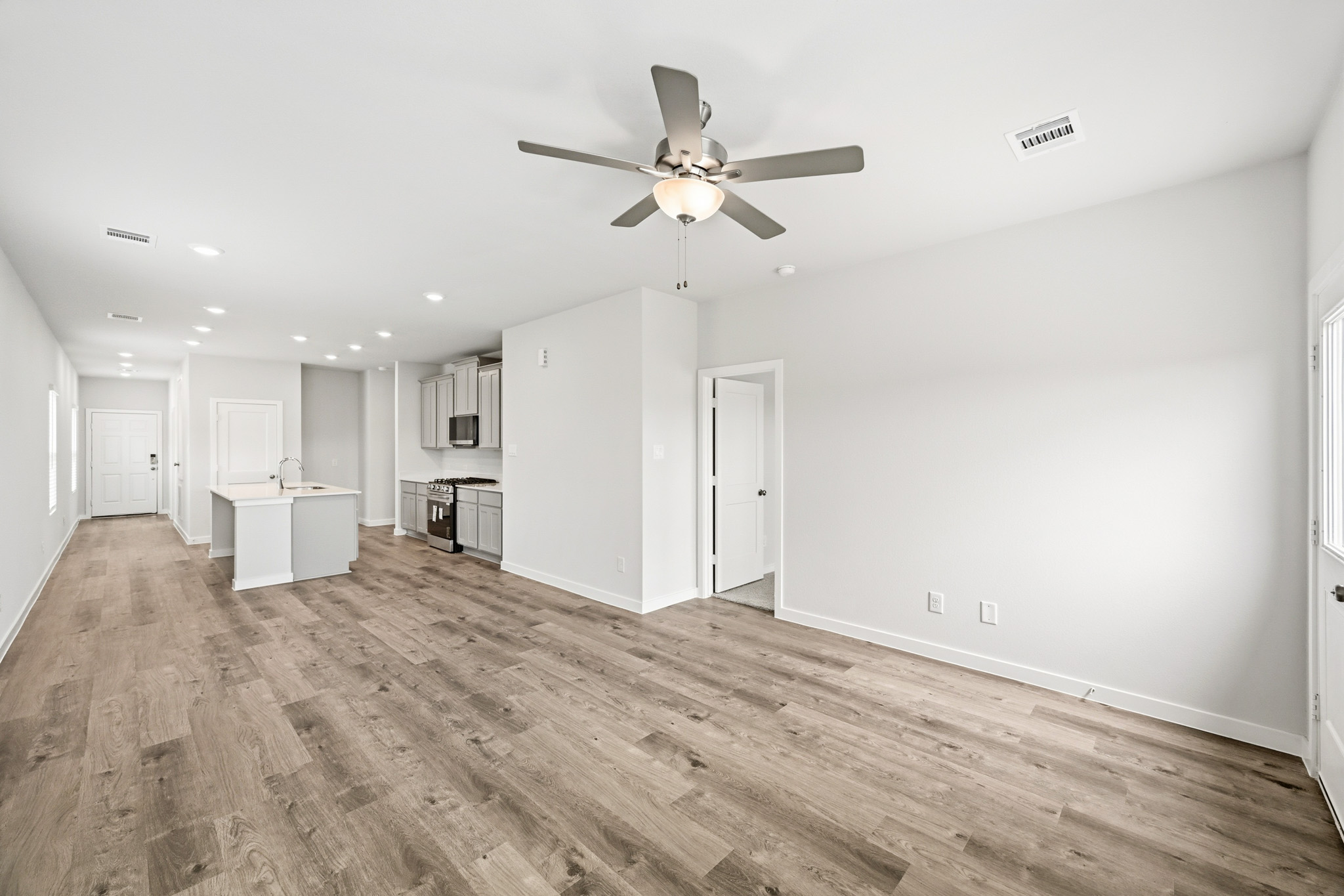A large empty room with a ceiling fan and wood floors.