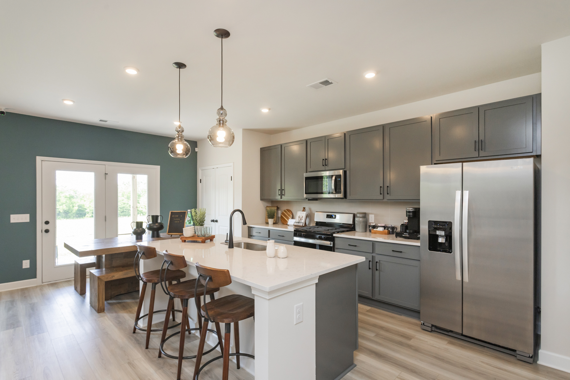 A kitchen with a fridge and stools.